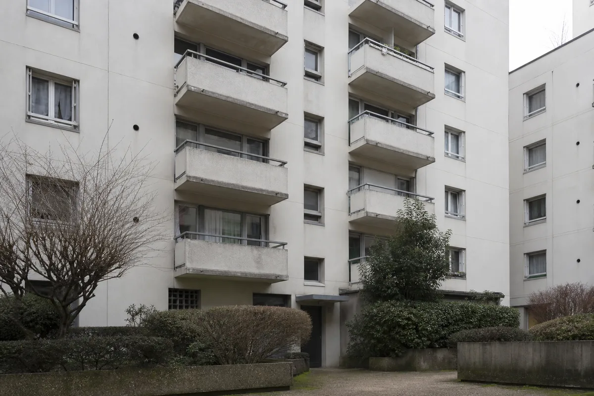 Façade d&rsquo;immeuble francilien des années 1970 vue depuis la cour, balcons alignés